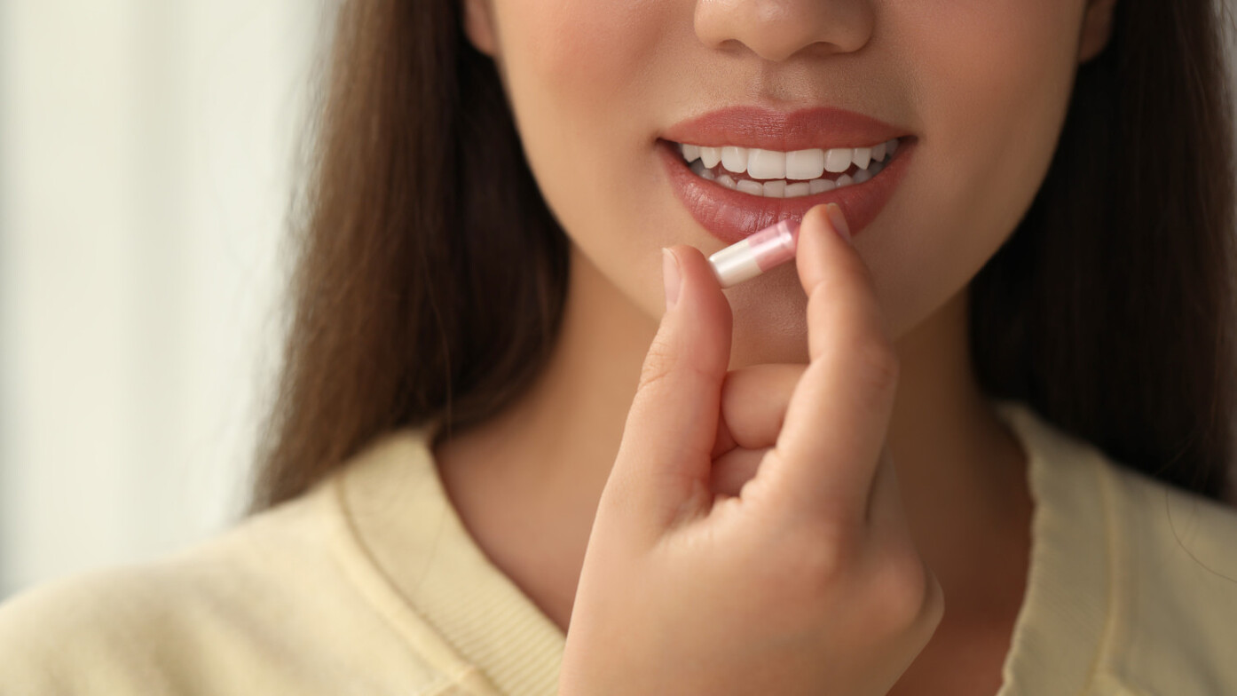 A person holding an NAD+ supplement thinking about about its role in anti-aging and longevity.